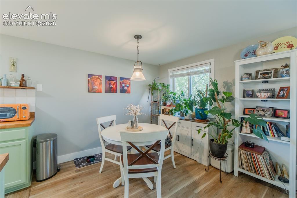 Image 9 of 31: Dining area featuring wood-finish flooring, a contemporary pendant light fi