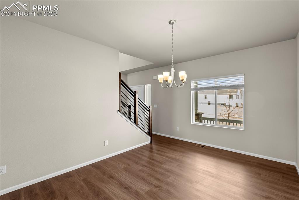 Image 6 of 43: Spare room featuring dark wood-style flooring and a chandelier