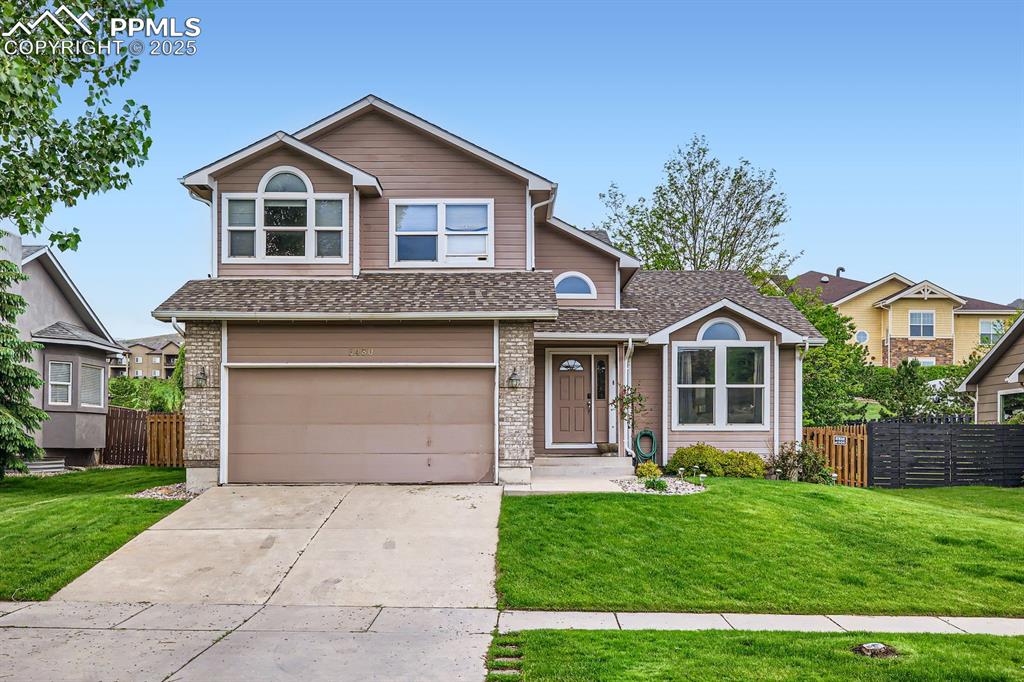 Caption: View of front facade with a garage, driveway, and a shingled roof