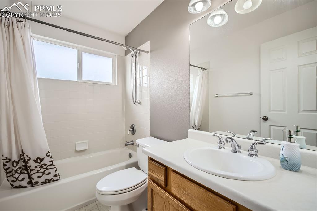 Image 13 of 18: Bathroom featuring shower / bath combo with shower curtain and vanity