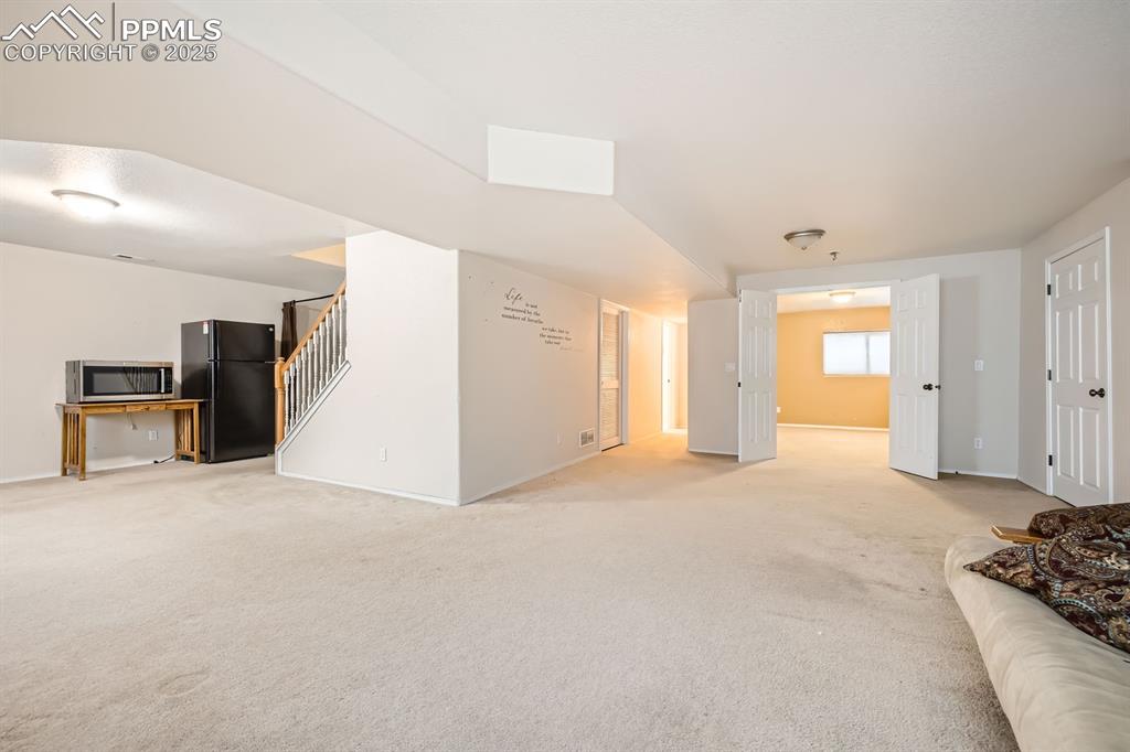 Image 14 of 18: Unfurnished living room with stairs and light carpet