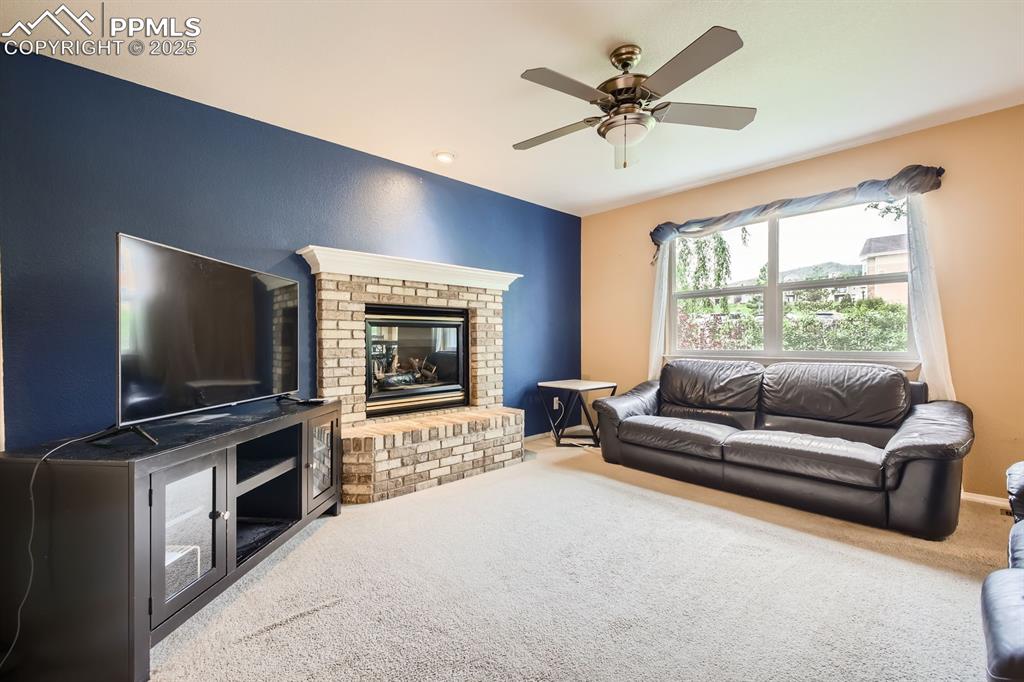 Image 6 of 18: Carpeted living room featuring ceiling fan and a fireplace