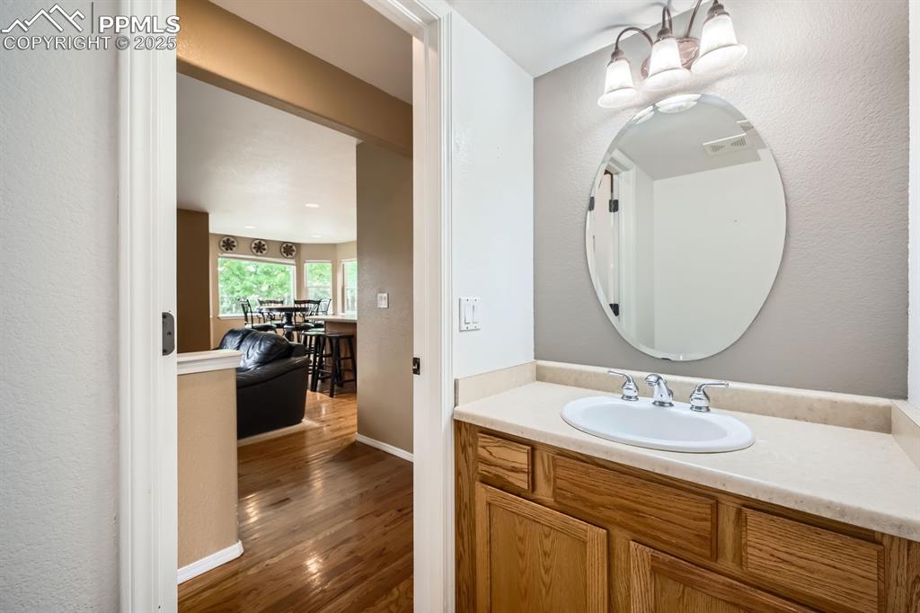 Image 7 of 18: Bathroom with wood finished floors, vanity, and a chandelier