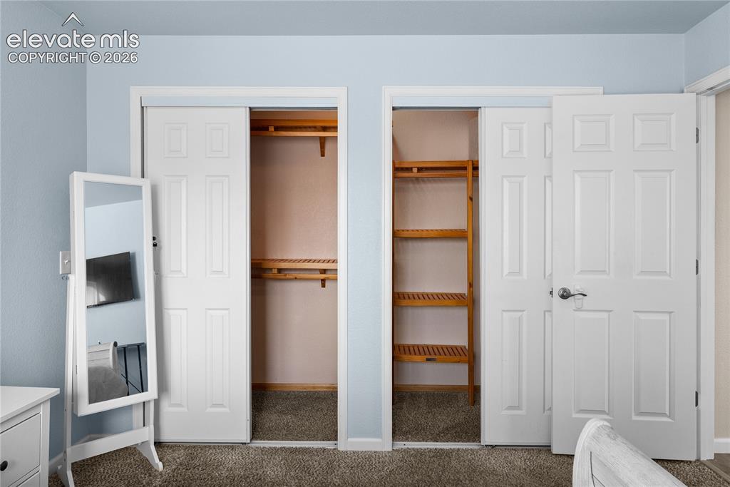 Image 12 of 42: Dual closets featuring paneled sliding doors and interior wood shelving