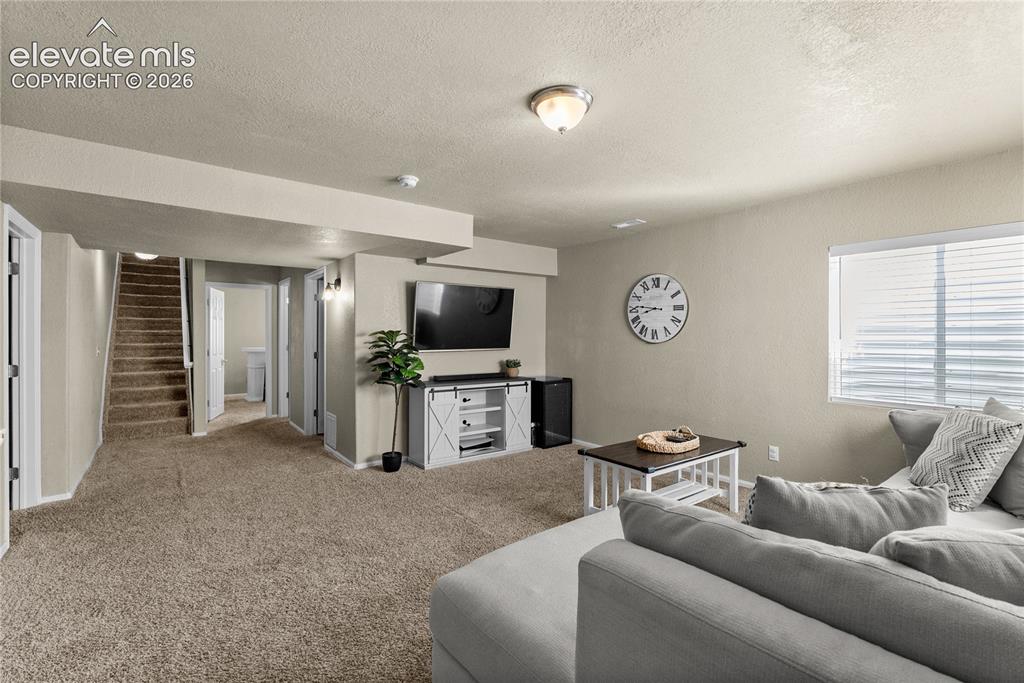 Image 17 of 42: Carpeted living area featuring a window with blinds, recessed lighting, and
