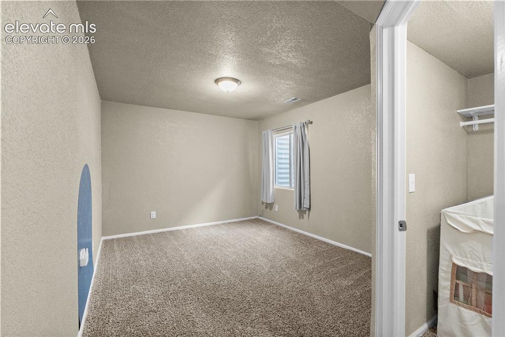 Image 19 of 42: Neutral-toned wall finishes, carpeted flooring, a window with blinds, and a