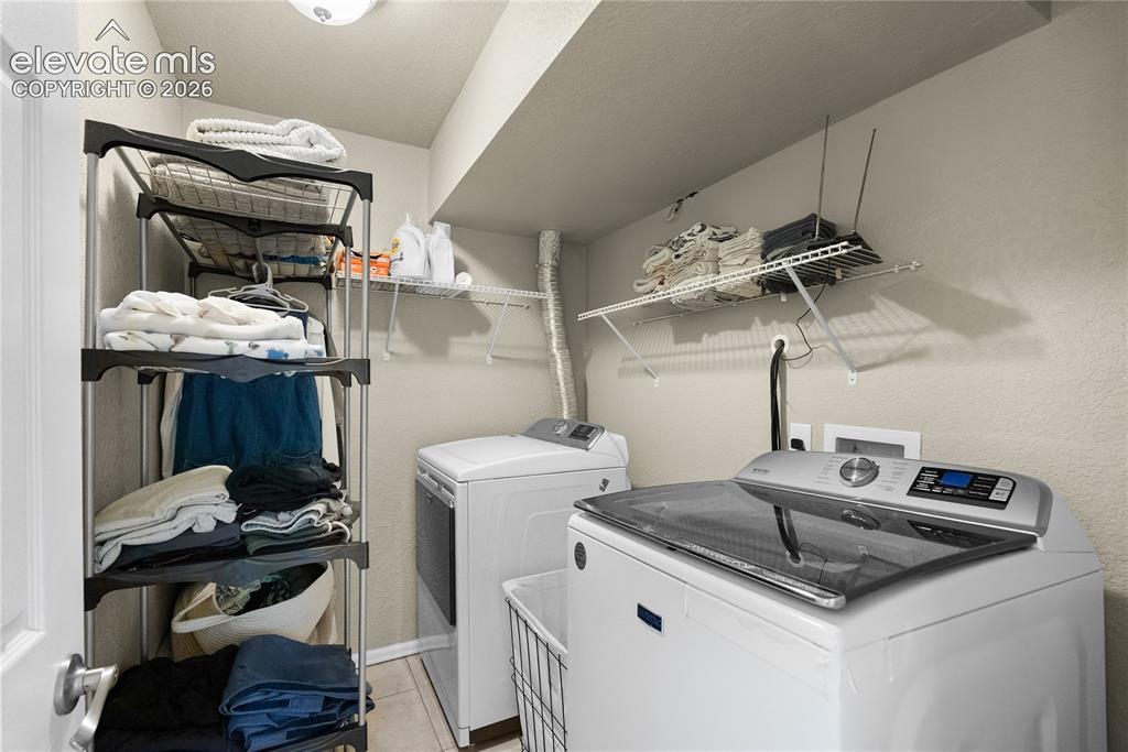 Image 22 of 42: Laundry area with tile flooring and a wall-mounted wire shelf