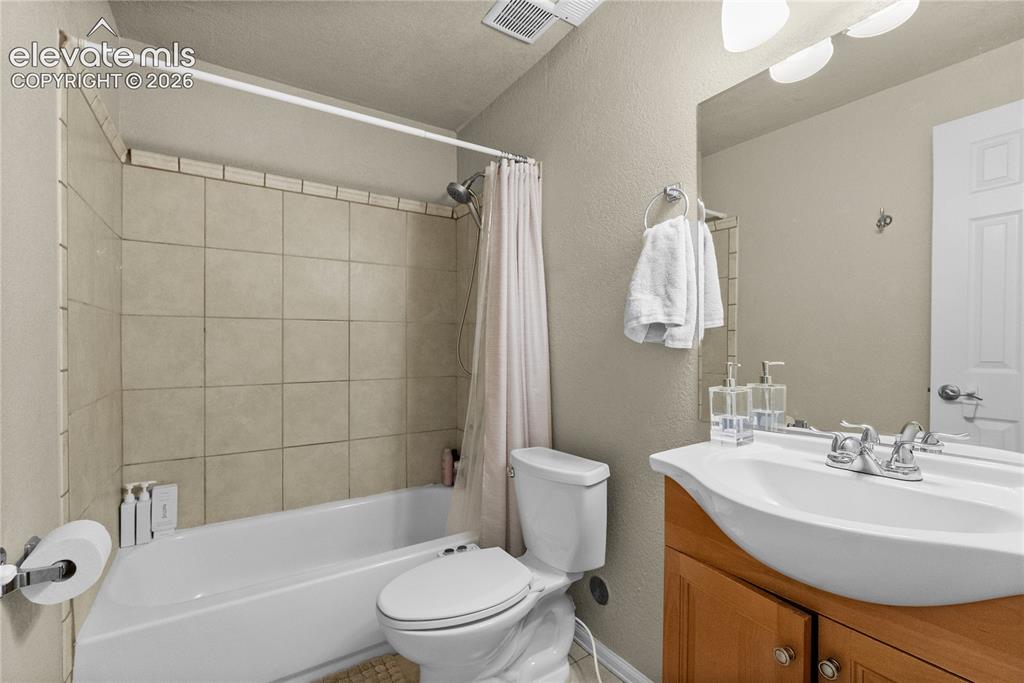 Image 23 of 42: Bathroom featuring a white bathtub, ceramic tile shower surround, toilet, w