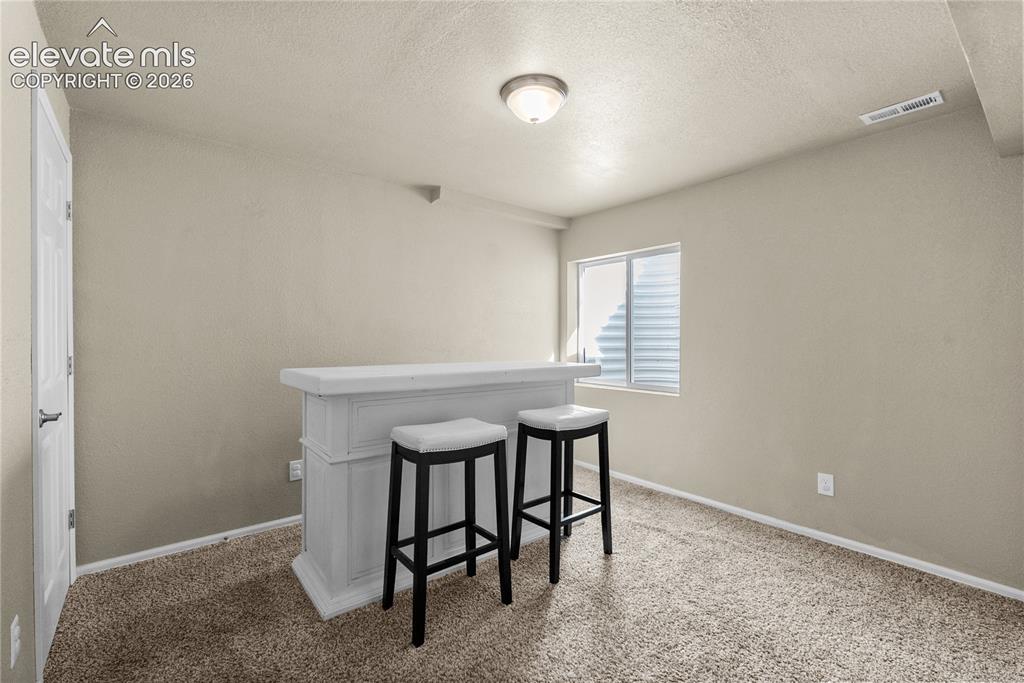 Image 24 of 42: Integrated bar counter, window with privacy blinds, neutral wall paint, and