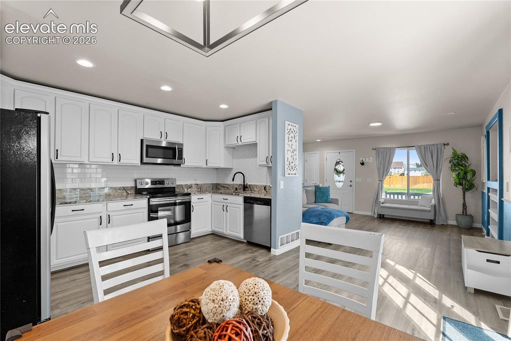 Image 27 of 42: Kitchen featuring white cabinetry, stainless steel appliances, a tile backs