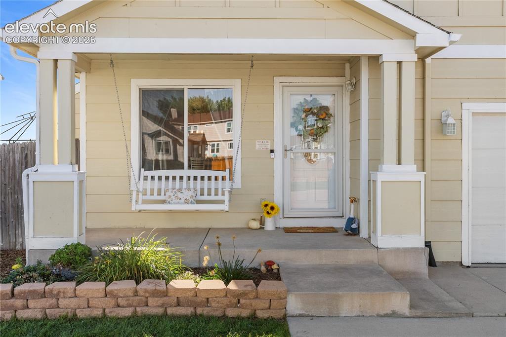 Image 3 of 42: Covered concrete porch with white-framed window, storm door, and decorative