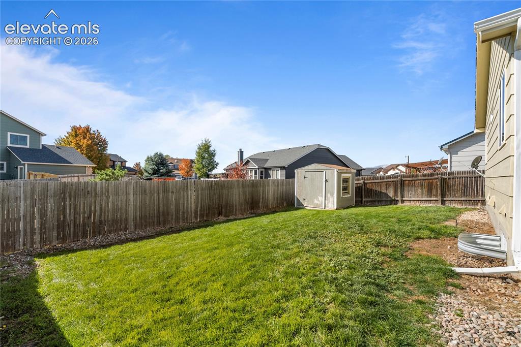 Image 32 of 42: Expansive fenced backyard with a storage shed and gravel border