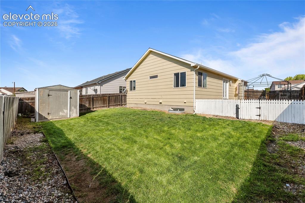 Image 33 of 42: Expansive backyard featuring a manicured lawn, white picket fence, and a st