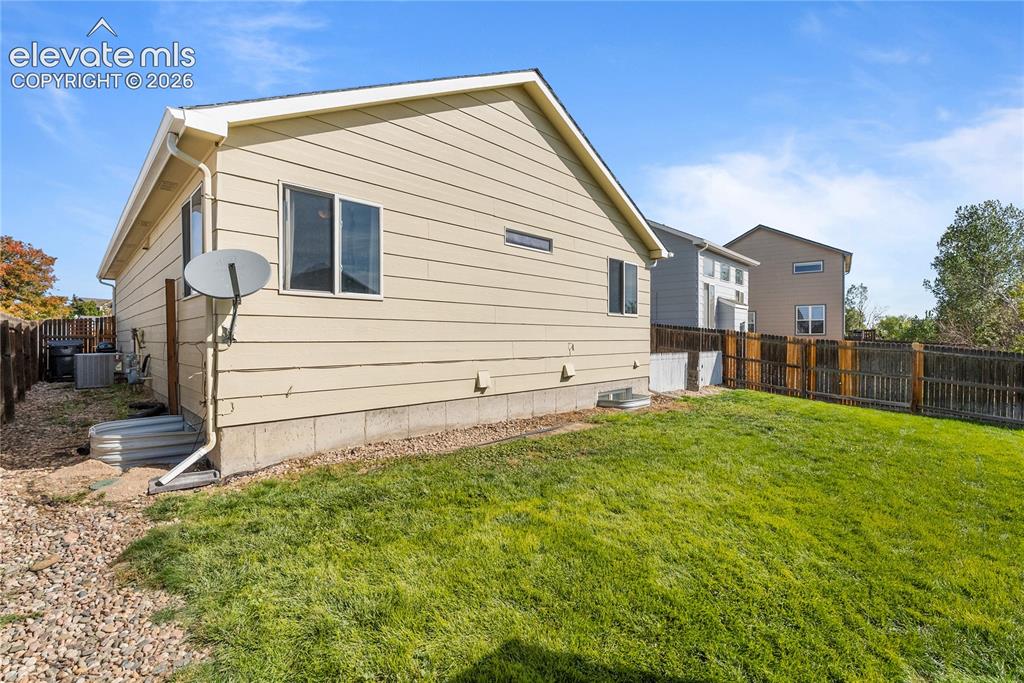 Image 34 of 42: Expansive backyard featuring a manicured lawn, full wood fencing, and a gra