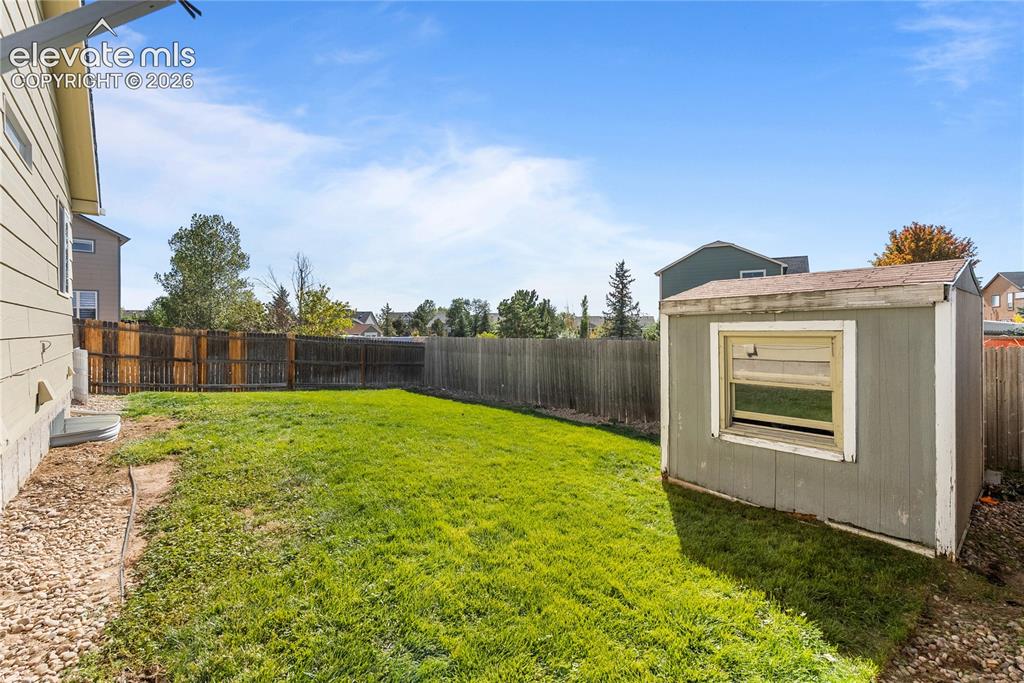 Image 35 of 42: Expansive grassy yard area with a wood-panel fence