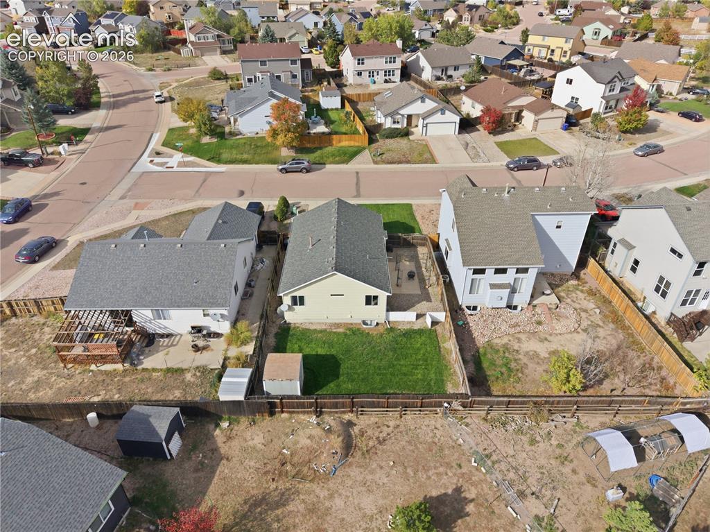 Image 37 of 42: Expansive backyard featuring a manicured lawn, wood fencing, and a storage