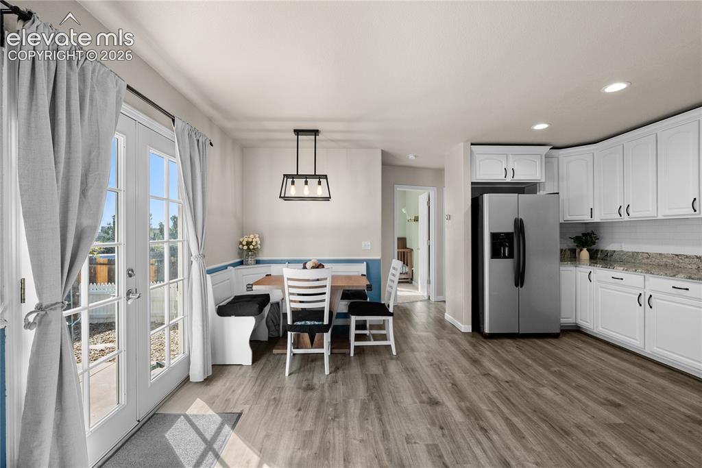 Image 5 of 42: Open-concept kitchen and dining area featuring white cabinetry with hardwar