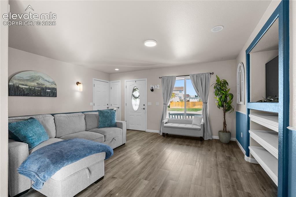 Image 6 of 42: Wood-finish flooring, recessed lighting, and a built-in media center with s