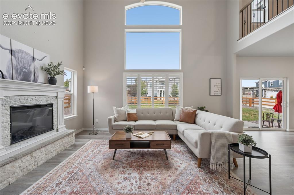 Image 10 of 43: Two-story living area with high ceilings, large windows with shutters, and 