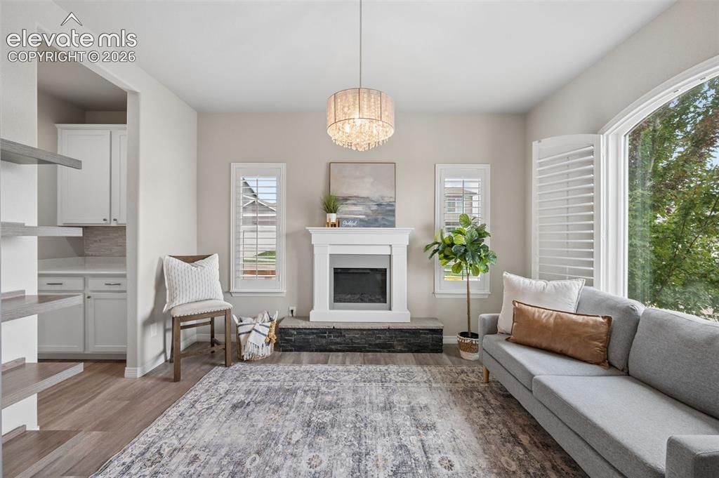 Image 12 of 43: Wood-finish flooring throughout, featuring a fireplace with stone hearth