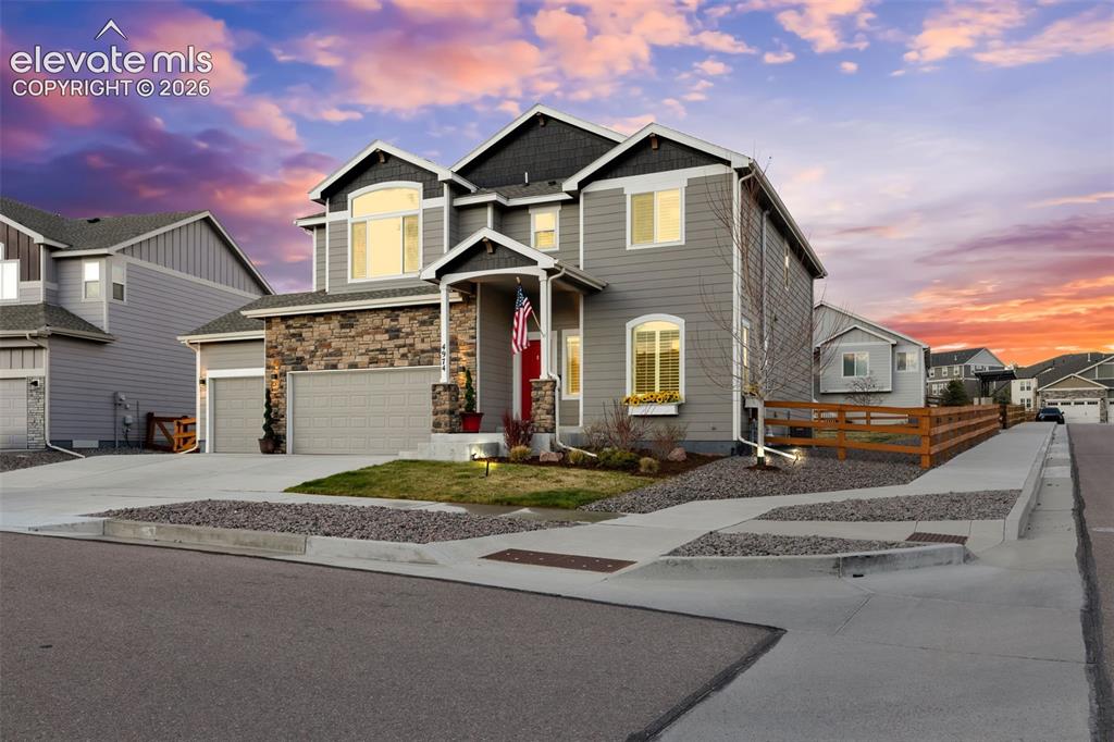 Image 2 of 43: Multi-story residence featuring a stone-clad façade, covered entry, and att