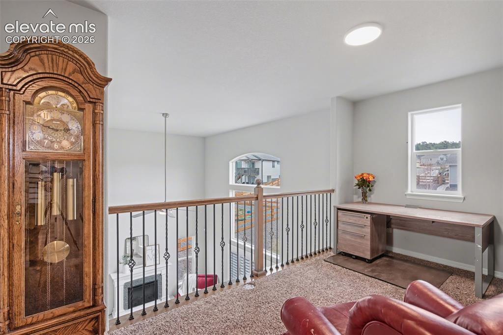 Image 23 of 43: Carpeted loft area with iron baluster railing, wood top railing, and white 