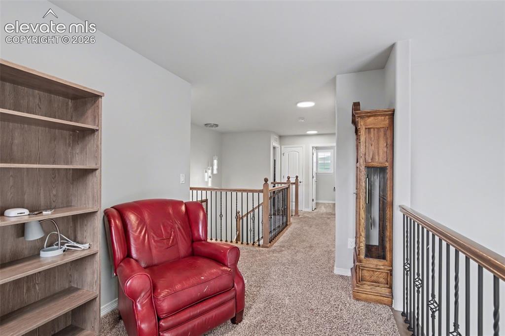 Image 24 of 43: Upper-level landing featuring carpet flooring, railing with wood-finish top