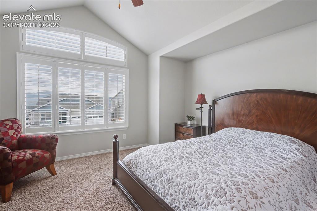 Image 27 of 43: Vaulted ceiling with a ceiling fan, wall-to-wall carpeting, and plantation