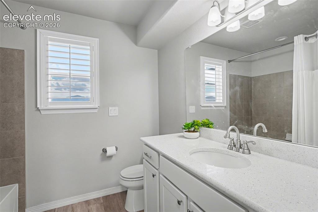 Image 28 of 43: White vanity with a light speckled countertop, dual-handle chrome faucet, a