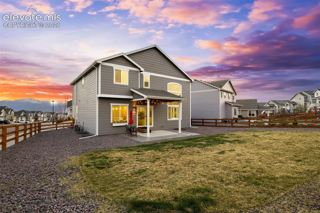 Image 33 of 43: Two-story home with gray siding, covered patio, gravel landscaping, and a w