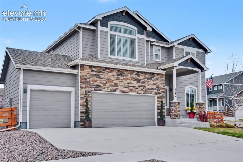 Image 34 of 43: Multi-level residence featuring gray siding, stone facade accents, a front
