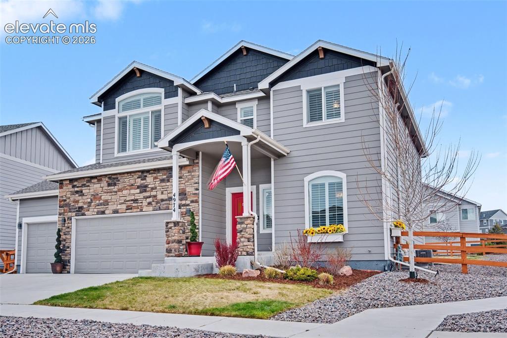 Image 35 of 43: Grey siding exterior with stone accents, covered front porch, and an attach