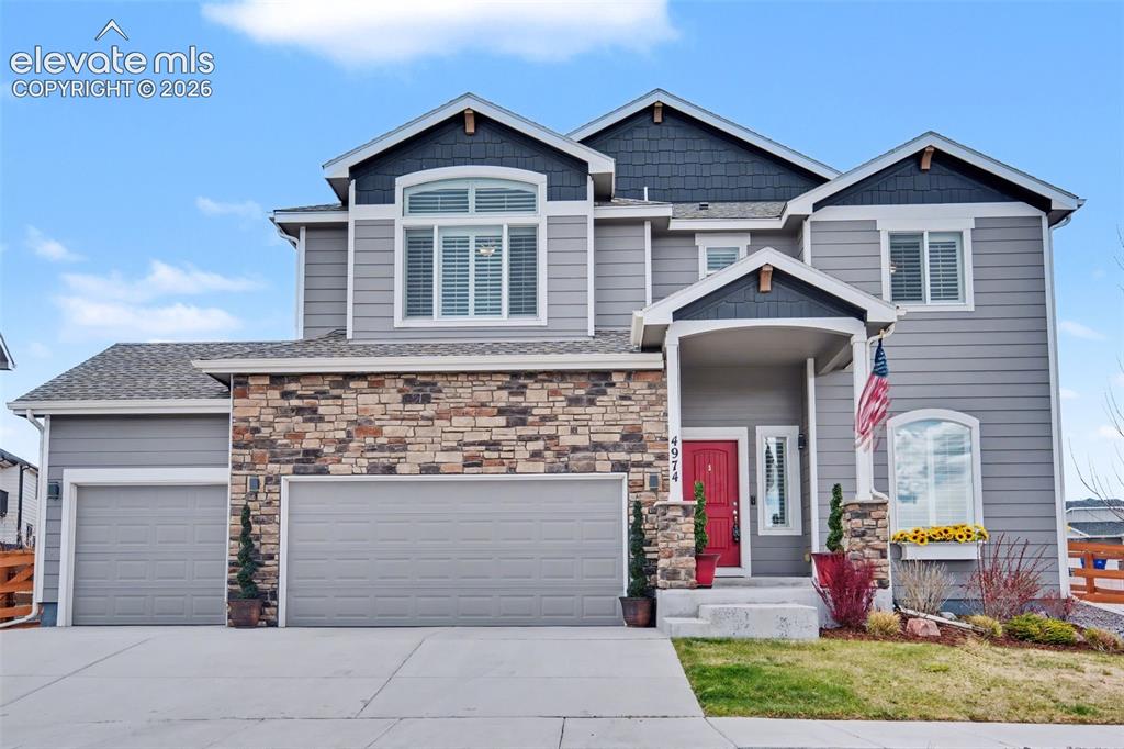 Image 36 of 43: Contemporary exterior with stone accent, dual garage doors, and covered ent