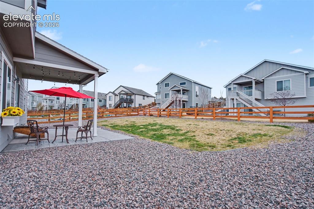 Image 37 of 43: Paved patio with covered area, string lighting, and planter box