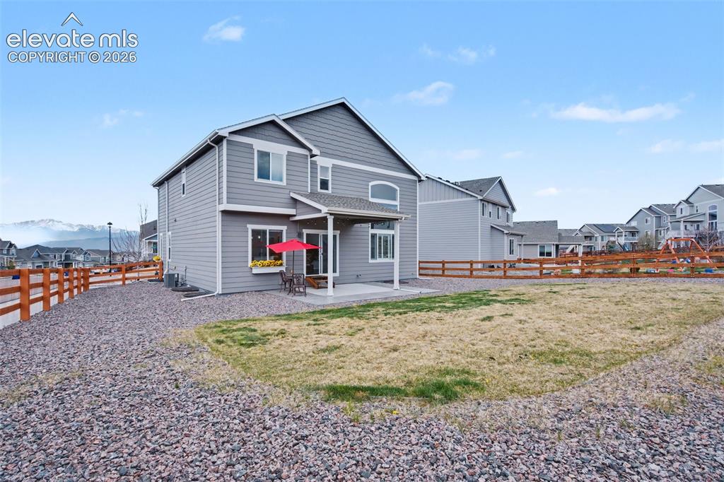 Image 39 of 43: Two-story residence with gray siding, featuring a covered patio and an expa