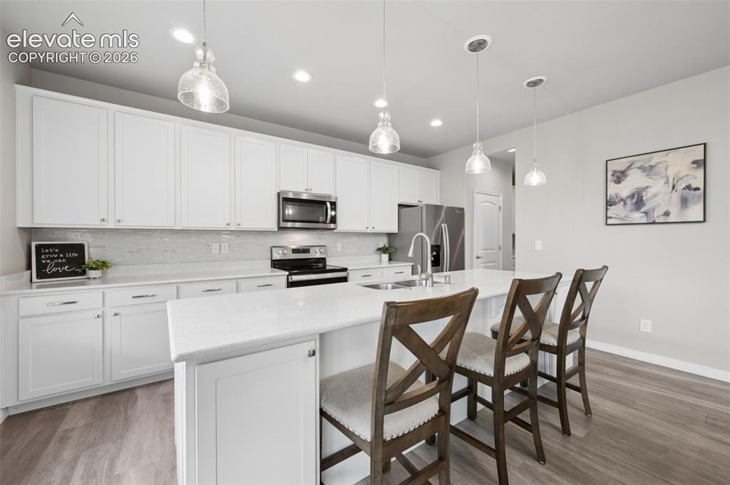 Image 8 of 43: White cabinetry, light-toned backsplash, stainless steel appliances, large