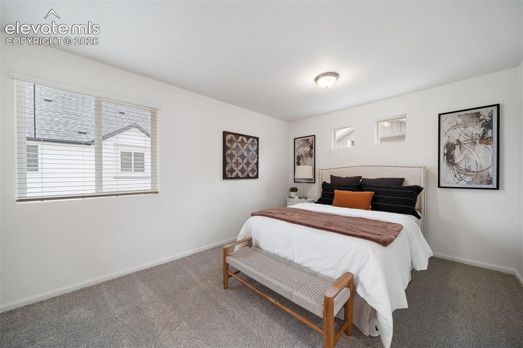 Image 21 of 25: Photos of a Model Home: Carpeted bedroom featuring a large window with blin
