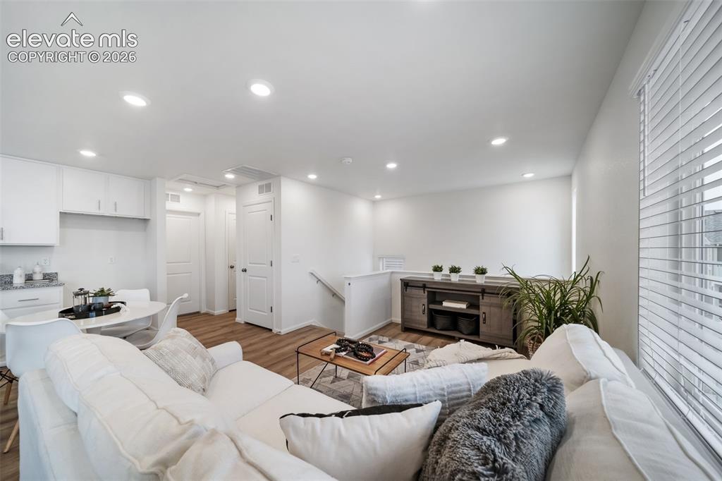 Image 7 of 25: Open-concept living area with white walls, wood-finish flooring, recessed l