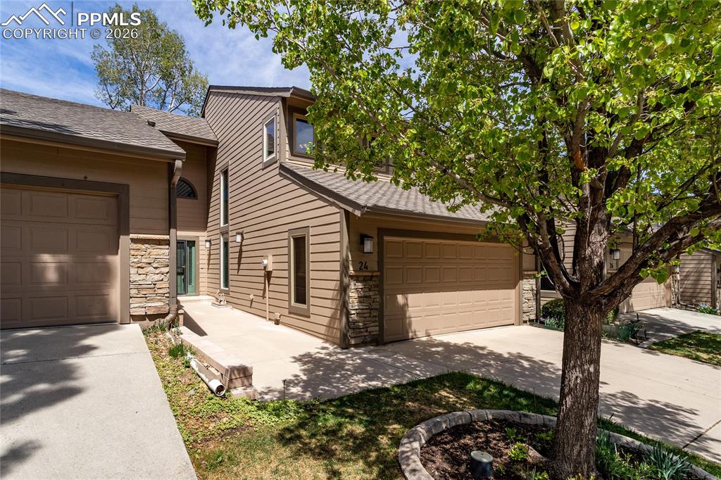 Caption: The property features a brown siding exterior with stone accents, a beige garage door, and a paved d