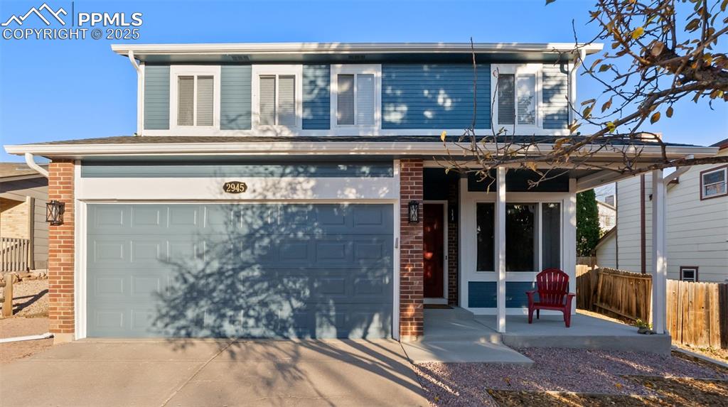 Caption: Traditional home featuring covered porch, brick siding, driveway, and an attached garage
