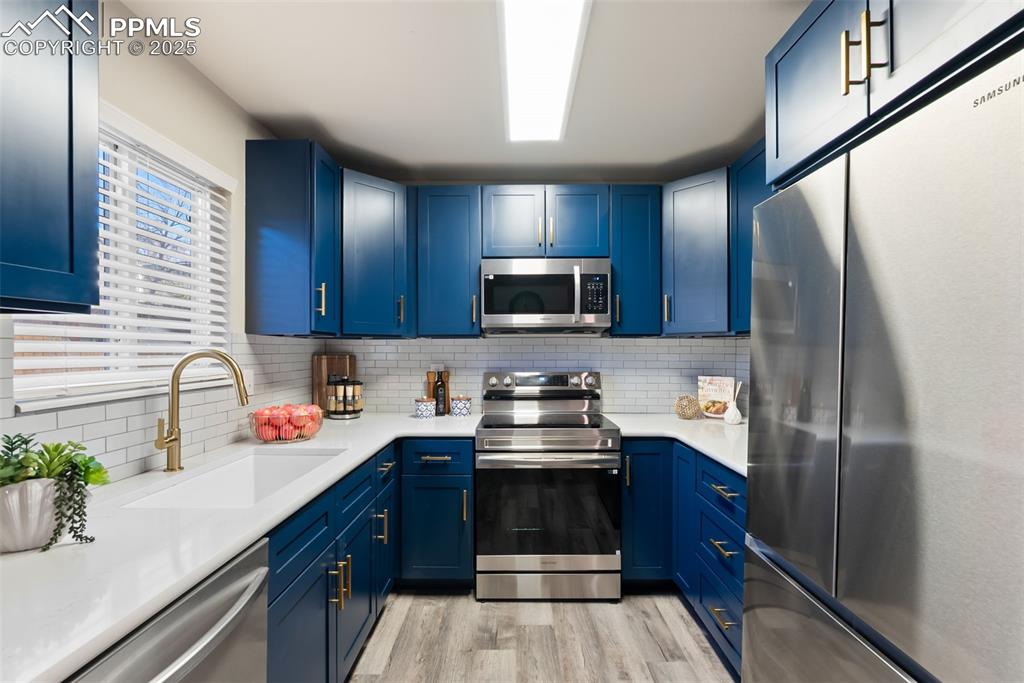 Image 12 of 50: Kitchen featuring appliances with stainless steel finishes, blue cabinetry,