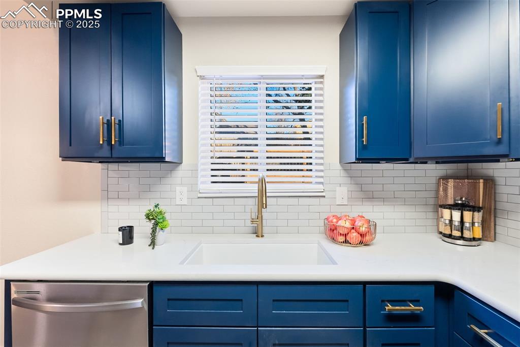 Image 13 of 50: Kitchen featuring blue cabinetry, stainless steel dishwasher, backsplash, a