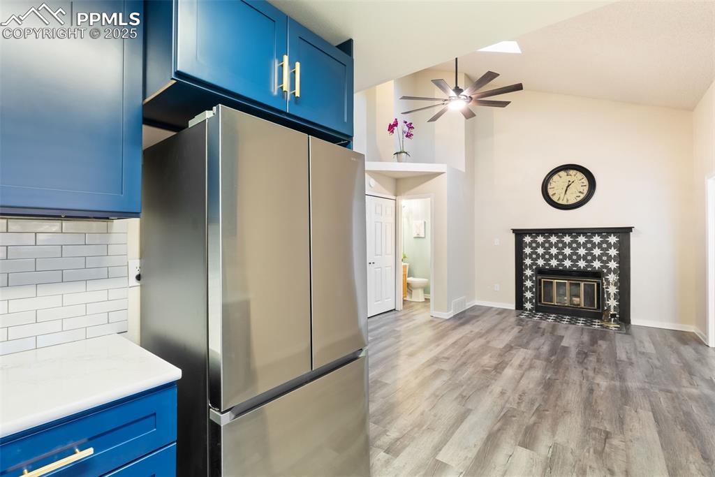 Image 14 of 50: Kitchen featuring blue cabinets, freestanding refrigerator, light wood fini