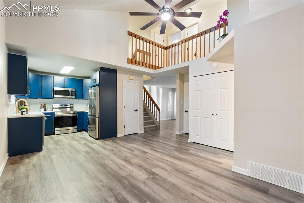 Image 17 of 50: Kitchen with blue cabinets, a high ceiling, light countertops, appliances w