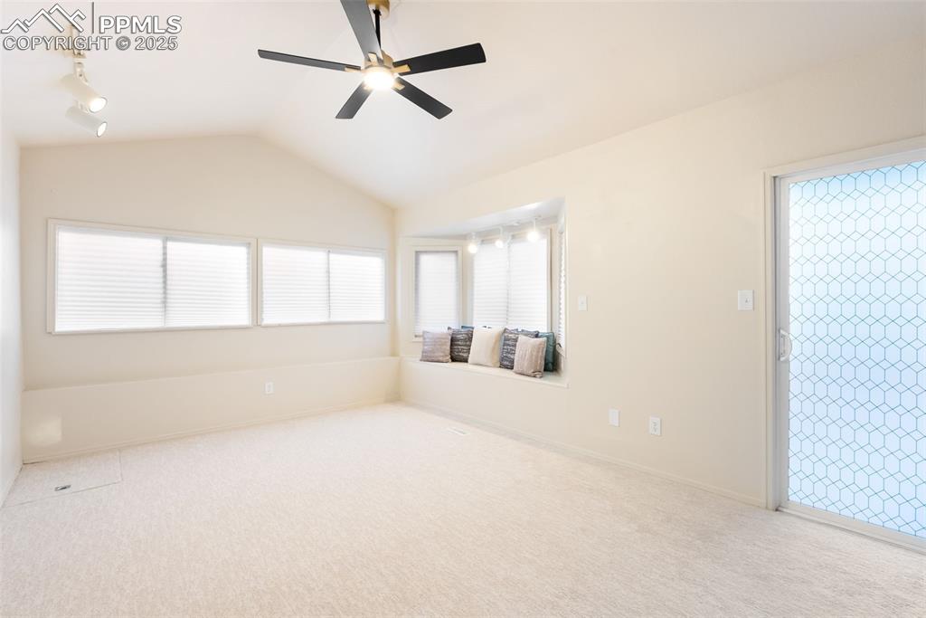 Image 18 of 50: Empty room featuring vaulted ceiling, light carpet, ceiling fan, and track 