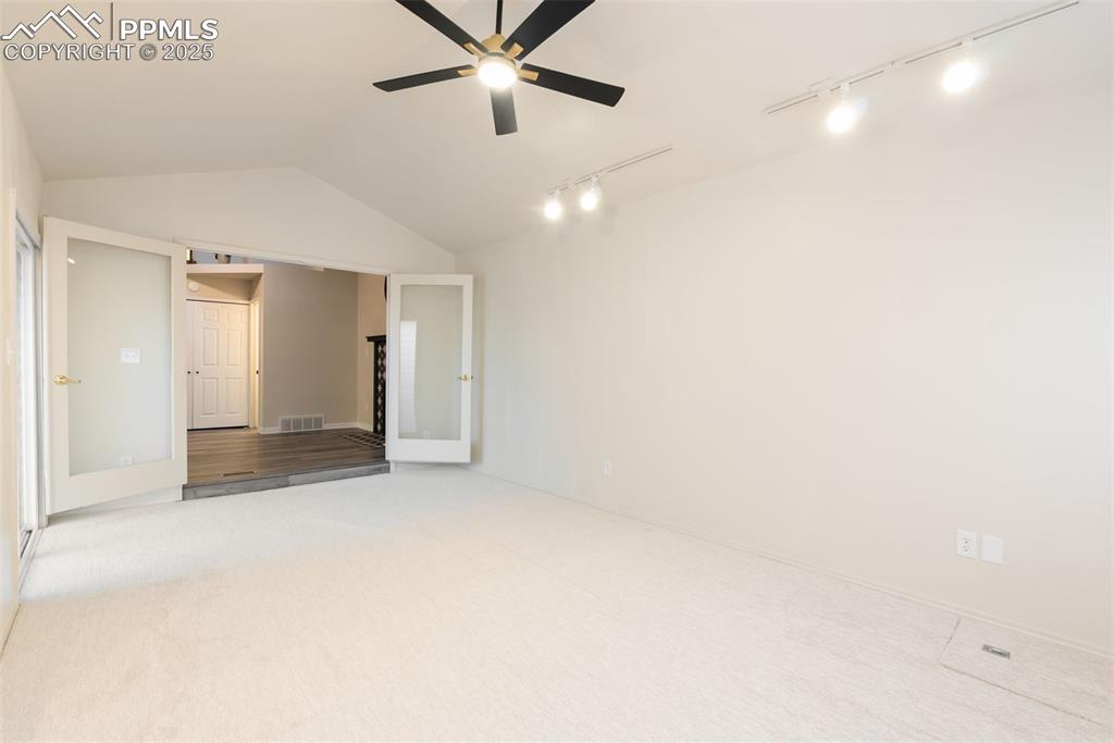 Image 21 of 50: Unfurnished bedroom with vaulted ceiling, rail lighting, carpet, and a ceil