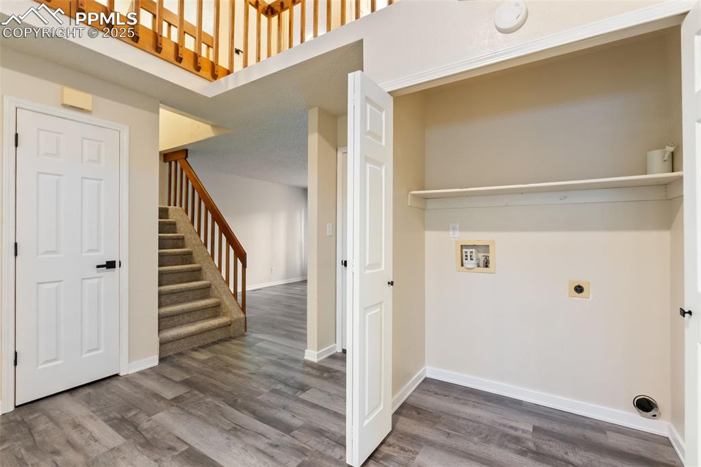 Image 23 of 50: Laundry room with a high ceiling, electric dryer hookup, dark wood-style fl