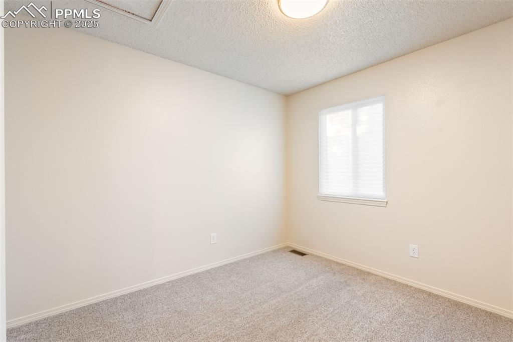 Image 24 of 50: Carpeted empty room featuring a textured ceiling and baseboards