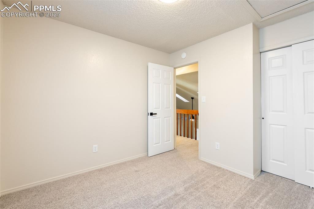 Image 25 of 50: Unfurnished bedroom with carpet flooring, a textured ceiling, and a closet