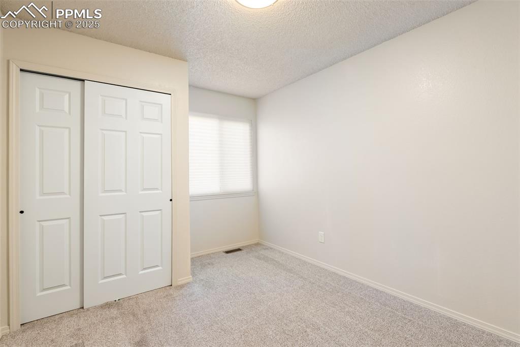 Image 26 of 50: Unfurnished bedroom featuring a textured ceiling, light colored carpet, and